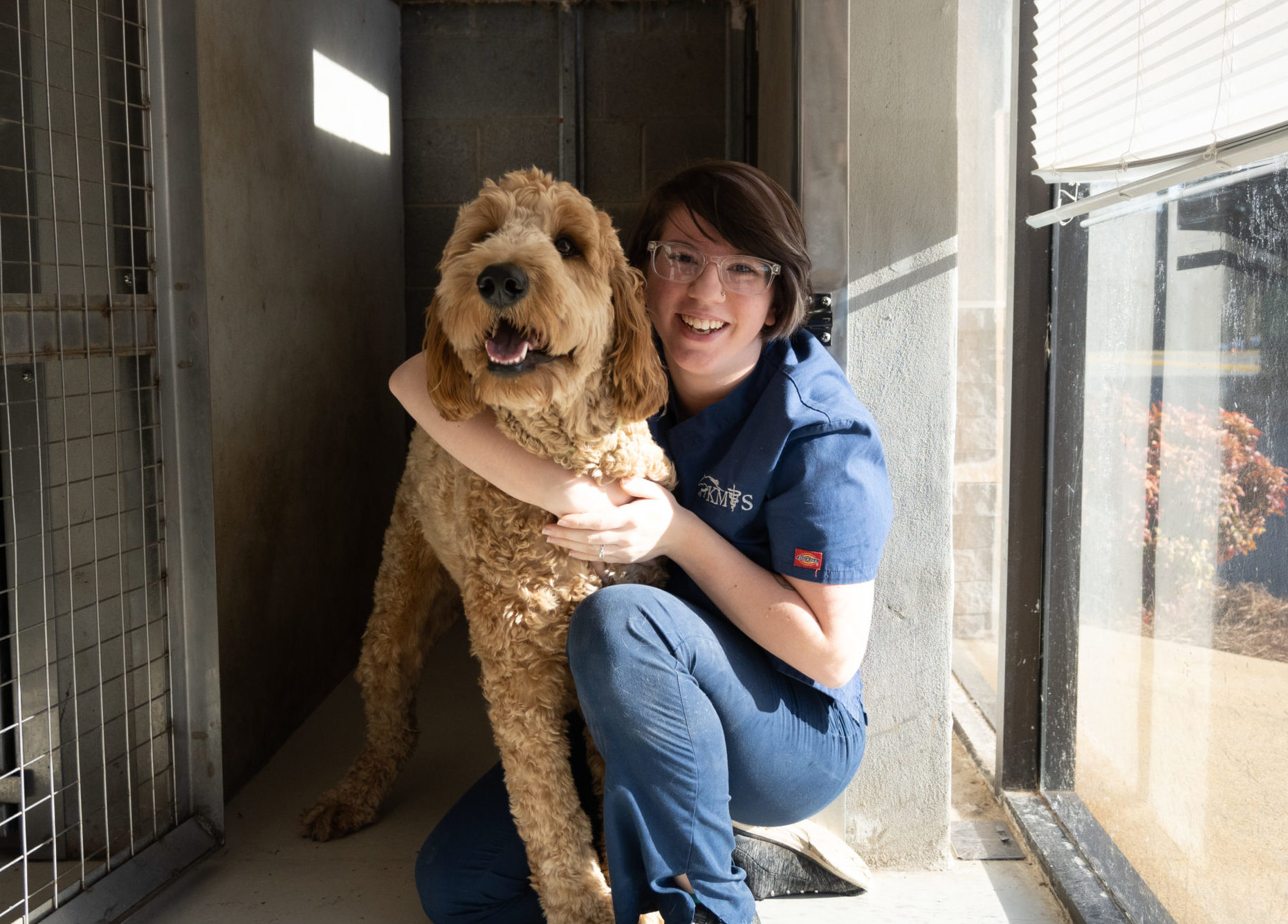 A large dog poses with a member of a veterinary staff during a boarding stay.